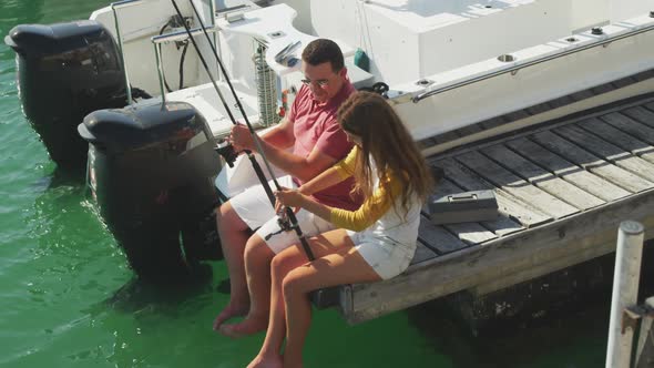 Side view of a Caucasian man and his teenage daughter fishing harbor side