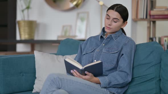 Latin Woman Sitting Reading Book on Sofa