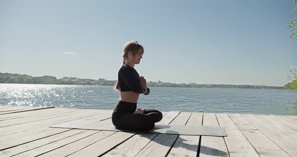 Young Blonde Woman Practicing Yoga on the Wooden Berth at Lake. Single Sport Healthy Training on