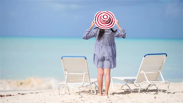 Young Beautiful Woman on White Sand Tropical Beach. Back View of Caucasian Girl in Hat Background