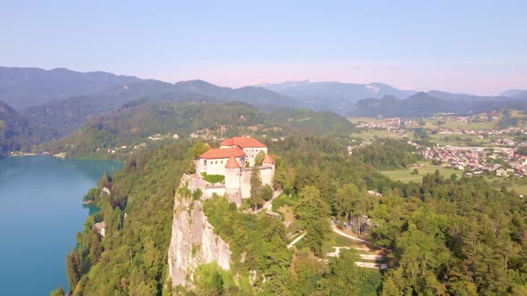 Point of interest aerial showcasing Bled Castle high above Lake Bled and the surrounding Julian Alps