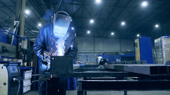 Male Welder Is Working with Metal in a Workshop. Professional Welder Working at Factory Facility.