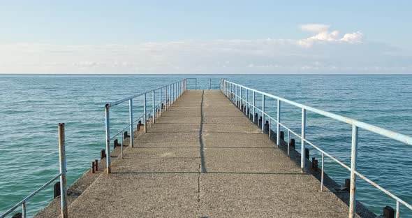 View of an Old Dilapidated Concrete Empty Pier Stretching Out to Sea on Sunny Day