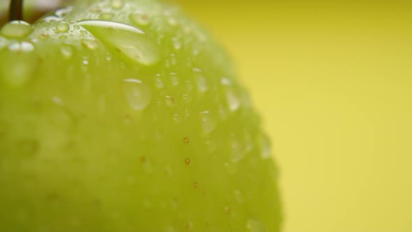 Spraying green sour apple with clean water in slow motion. Juicy fresh fruit