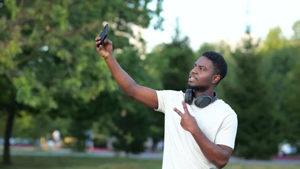 African American Man Makes Selfies on Smartphone in Park