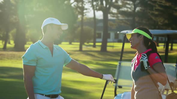 Happy couple interacting with each other while playing golf