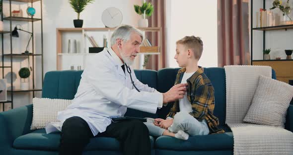 Doctor Examining Boy Patient's Heartbeat Using Stethoscope During Home Visit