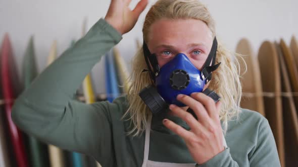 Caucasian male surfboard maker wearing a breathing face mask