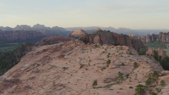 Smooth and wide tracking pan with drone over sunset pink cliffs and majestic views within Zion Natio