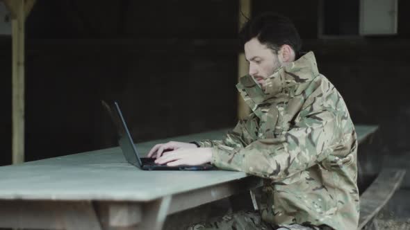 Army soldier on laptop at base camp