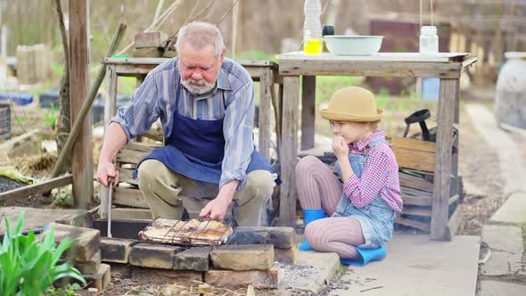 Granddaughter Helps Grandfather Cook Barbecue