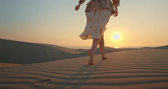 Woman Running Toward the Sunset By Scenic Wavy Texture Sand. Close Up Model Legs