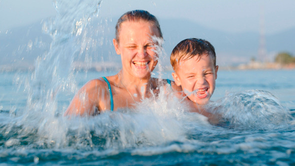 Little Son And Mother Fooling In Water