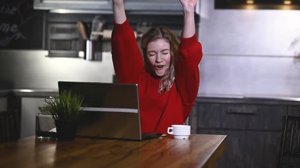 Portrait of happy girl enjoying unexpected good news on a laptop in kitchen