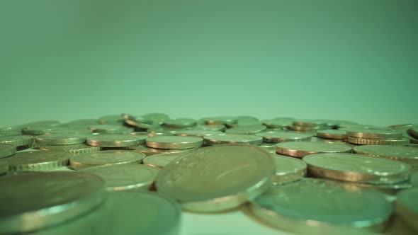 Coins Fall Down Onto Pile on White Background at Green Light