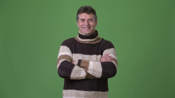 Mature Handsome Man Wearing Turtleneck Sweater Against Green Background