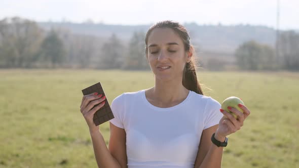 Girl Trying To Choose Between Chocolate And Apple