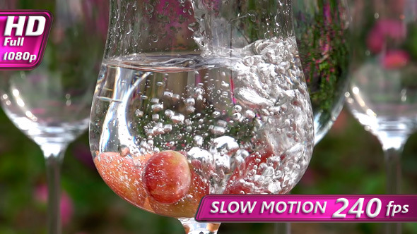 Water is Pouring into a Glass with Grapes