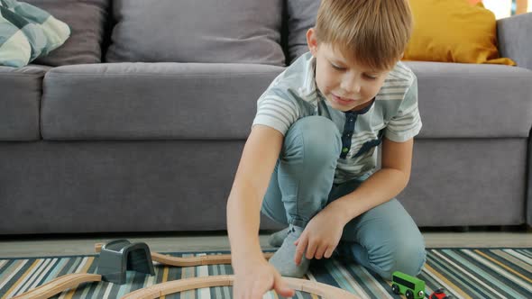 Happy Child Boy Playing with Wooden Toy Cars at Home Enjoying Game in Free Time