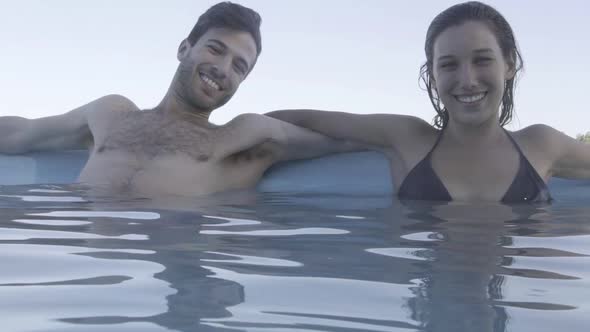 Couple in pool leaning against wall together
