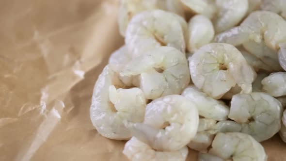 Raw peeled shrimp on a brown butcher paper.