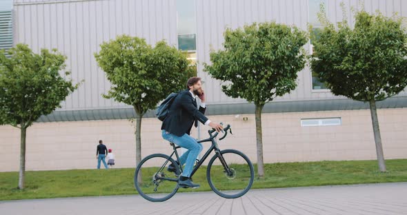 Office Worker Talking on Phone while Getting to His Work on Bike