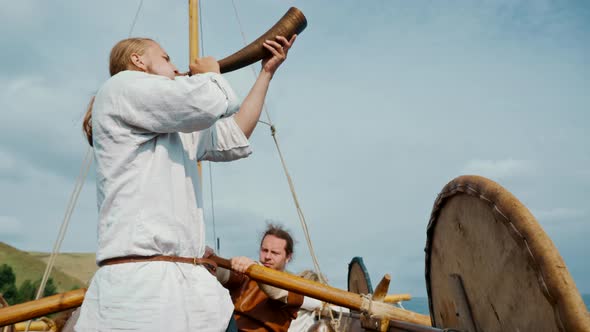 Vikings Sail on an Old Ship with a Raised Sail on a Calm River