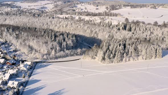 Drone flight over a winter landscape with a little town left sided, smooth flight going slowly down.