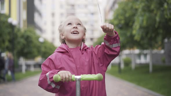 Cheerful Smiling Little Girl Holding Balloon and Looking Up and at Camera. Portrait of Beautiful