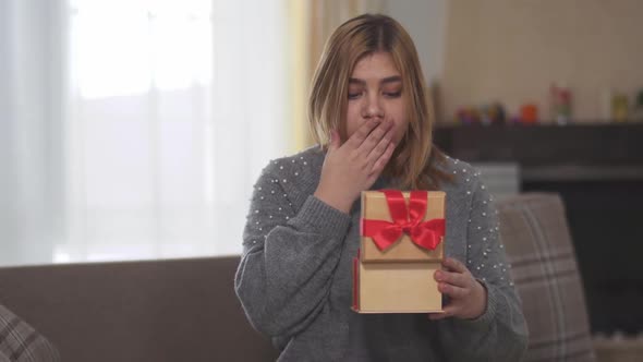 Portrait of Happy Joyful Bbw Opening Gift Sitting on Sofa in Room