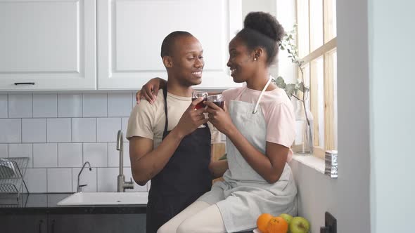 Married Couple Clink Glasses of Wine in the Kitchen