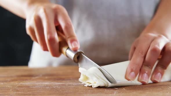 Woman slicing dough on chopping board