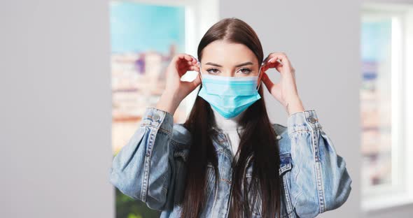 Closeup of a Brunette Model Putting on a Protective Medical Face Mask and Looking at