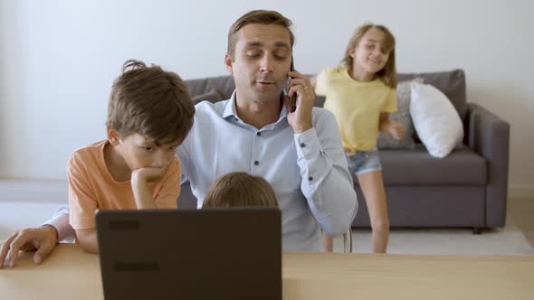 Caring Dad Talking on Smartphone Sitting at Table