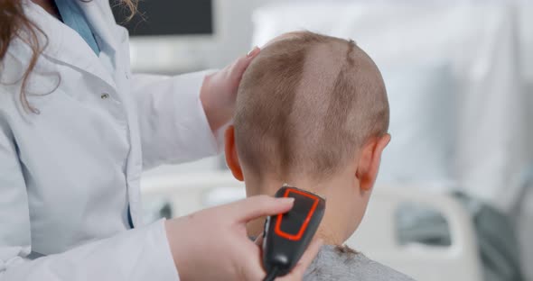 Back View of Kid Sitting in Hospital Ward and Having Hair Cut Preparing for Brain Surgery