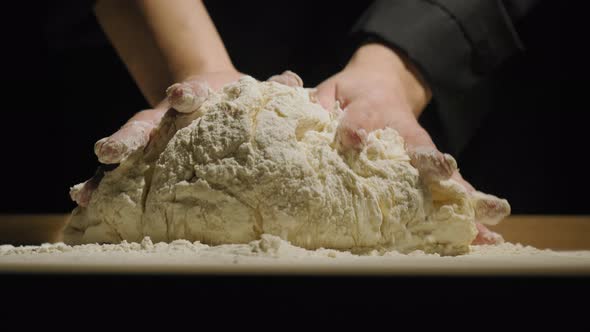 Hands of Baker Kneading Dough Isolated on Black Background