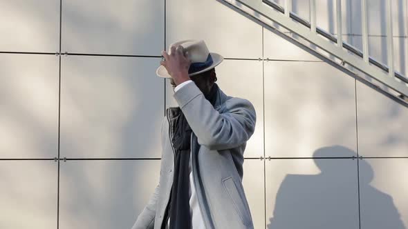 African Man Trying on Hats on a Brick Background