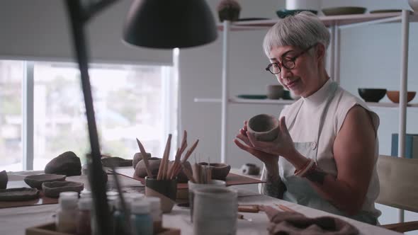 Asian elderly woman enjoying pottery work at home.