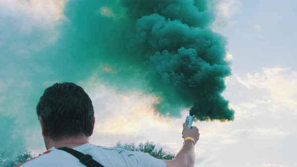 Man Having Fun with Colorful Smoke Flares Against the Sky. Slow Motion