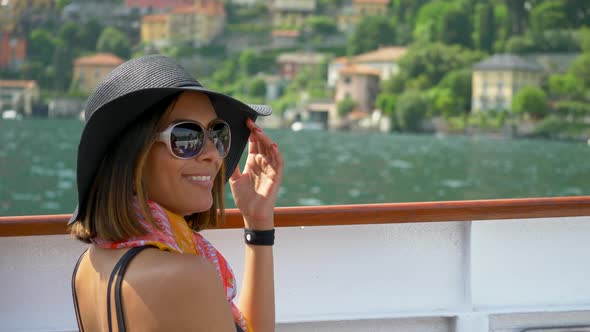 A woman wears a hat while traveling to luxury resort town on a ferry near Lake Como, Italy, Europe