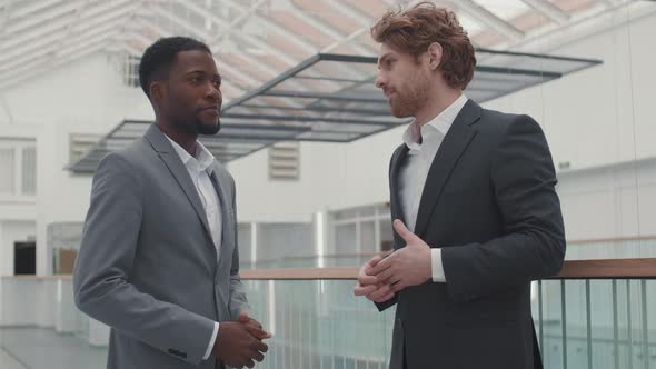 Two Diverse Businessmen Talking in Hall