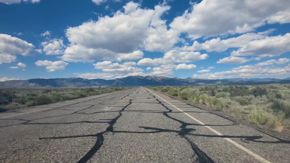 Small Asphalt Road Surrounded By Desert with Clouded Blue Sky.