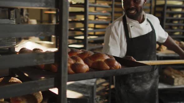 Animation of happy african american male baker holding wooden spatula with challah