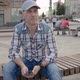 Caucasian Man Sitting on Bench in Square City Holding Smartphone Looking Ahead - VideoHive Item for Sale
