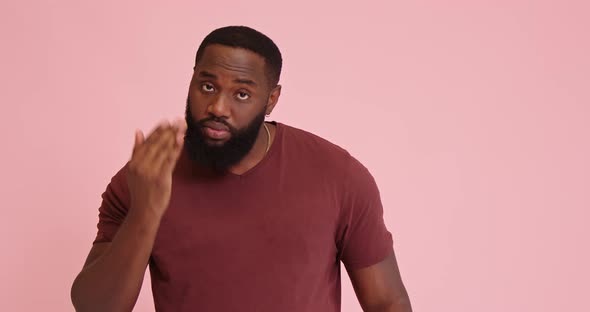 Young African American Man Touch Eyebrows on Pink Background