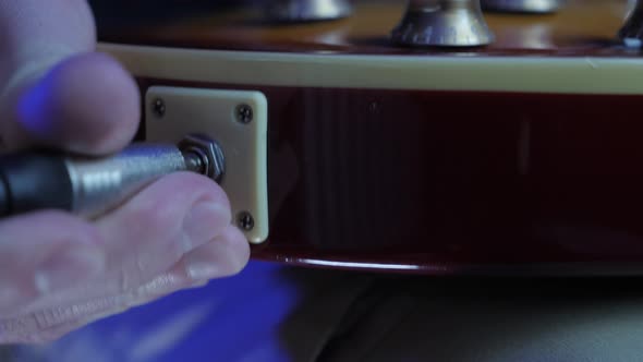 Guitarist unplugs instrument cable jack from electric guitar