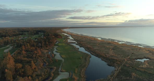 Golf Course Aerial View with Lakes and Green Islands on Sea Coast at Sunset