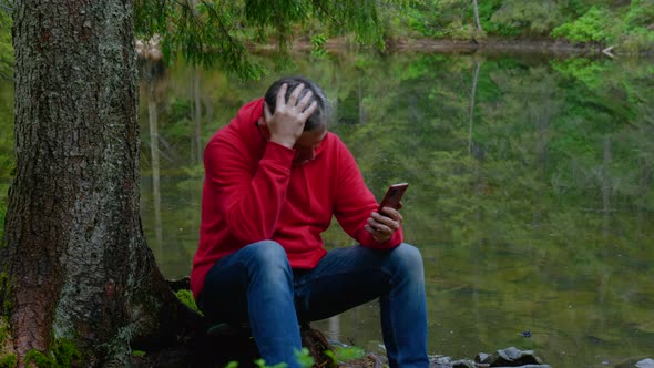 Bearded Man with a Phone Near a Mountain Lake