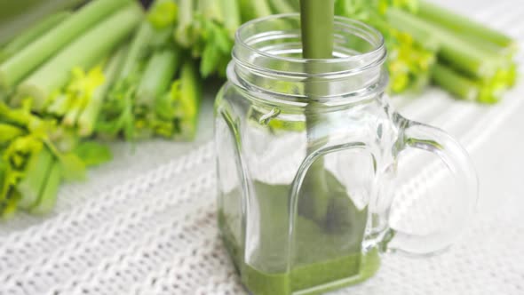 Pouring Green Smoothie With Celery In A Glass Jar.