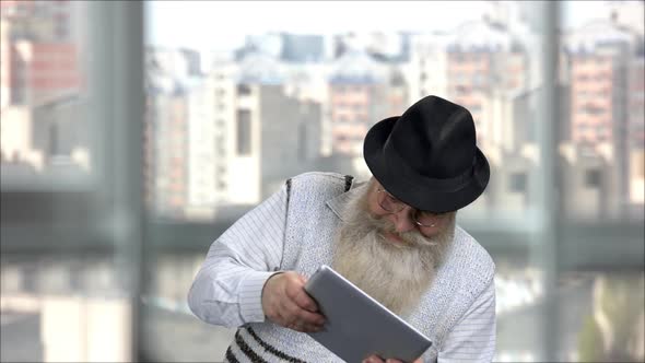 Old Bearded Man Playing Video Game As a Child on a Tablet Pc